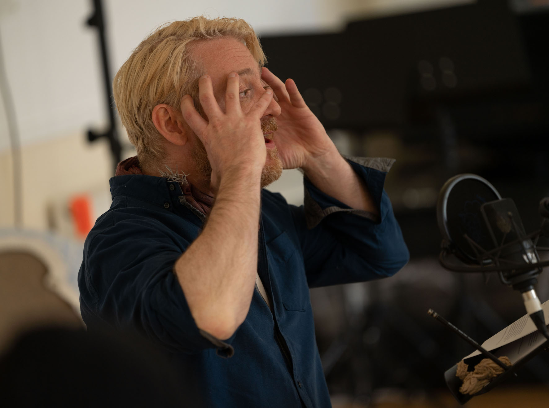 An actor holds their hands up to their face, performing being shocked