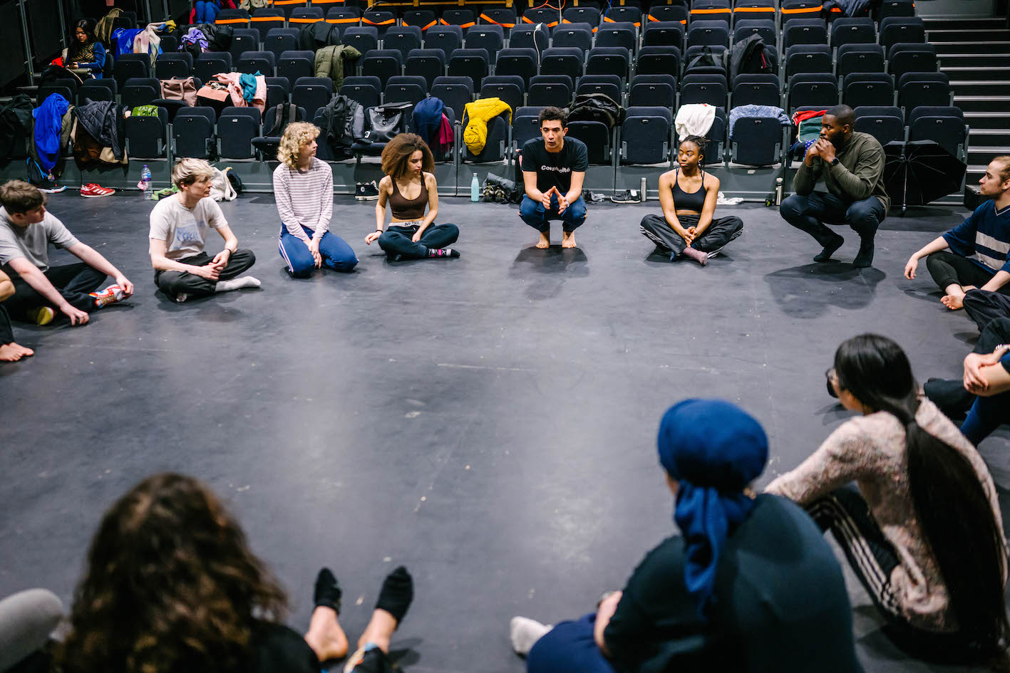 The participants sit in a circle, while their facilities crouch, speaking to them.
