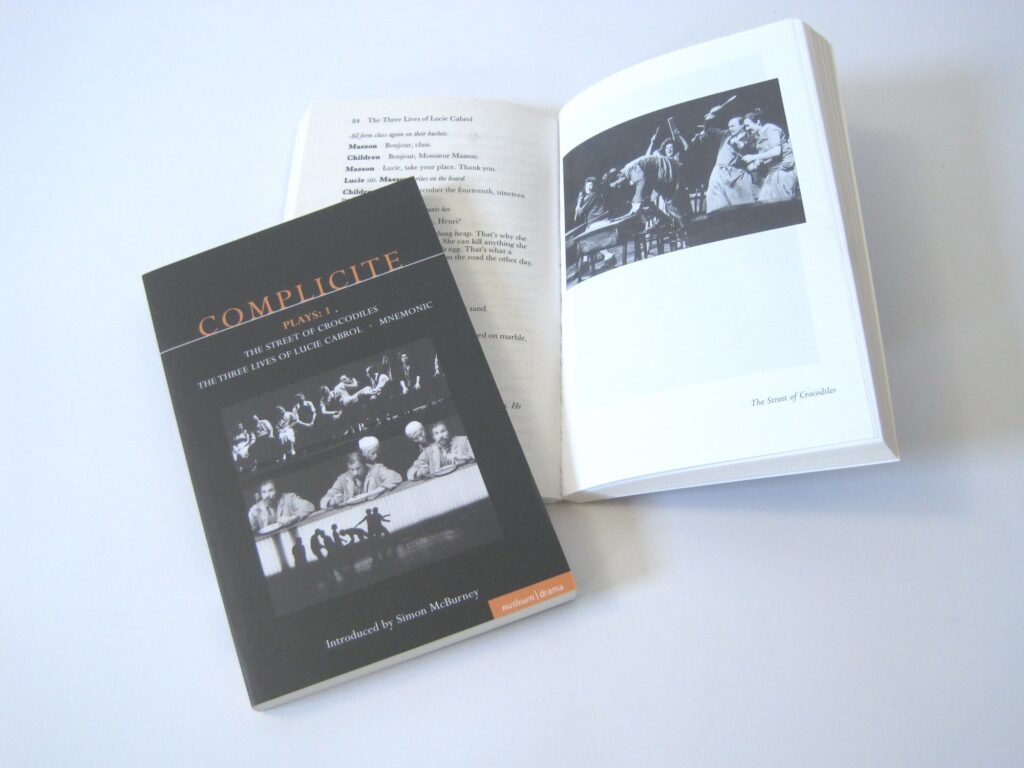 Two play texts of Complicité Plays 1, one closed and lying on top of the other play text, which is open. Both display black and white pictures from The Street of Crocodiles, The Three Lives of Lucie Cabrol and Mnemonic.